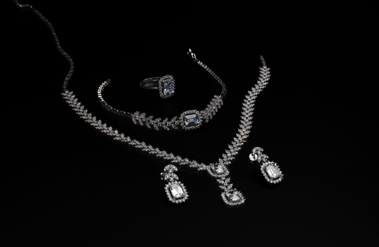 why-choose-us-01 Elegant diamond jewelry set including necklace, bracelet, ring, and earrings on a black backdrop.