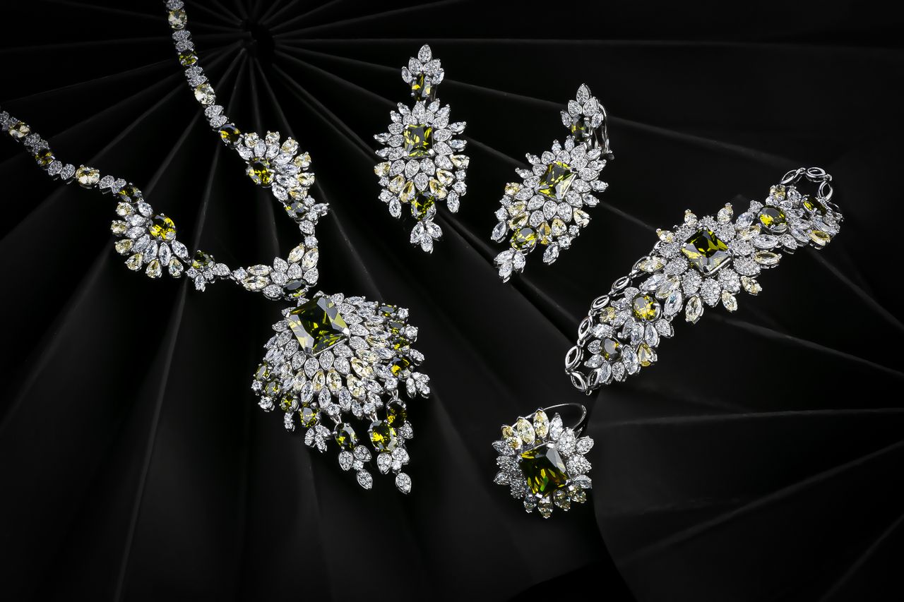 our-story-01 Luxurious set of diamond and emerald jewelry on a black background, highlighting elegance.