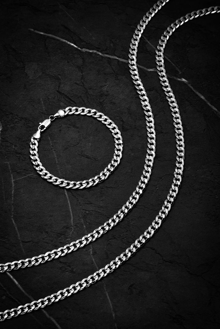 why-choose-us-02 Stylish silver chain and bracelet set on a dark textured background, perfect for fashion lovers.