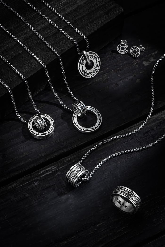 Elegant collection of silver necklaces, rings, and earrings on dark wood.